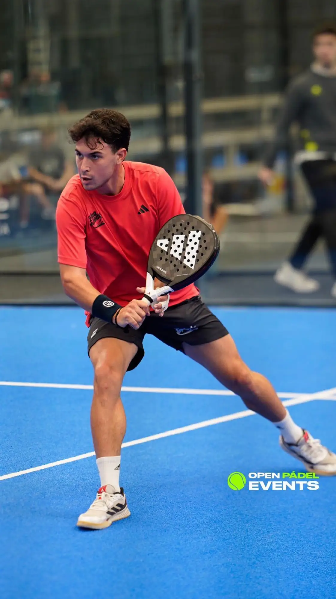 Player striking a forehand on a blue padel court